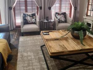 sala de estar con mesa de centro y 2 sillas en La Casa Guest House, en Bloemfontein