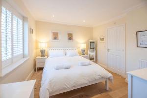 a white bedroom with a large bed with white sheets at Fromus Rise, Saxmundham in Saxmundham