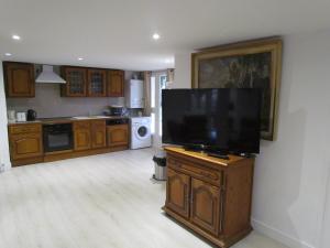 a kitchen with a flat screen tv on a wooden cabinet at gîte de la Claveille in Bergerac