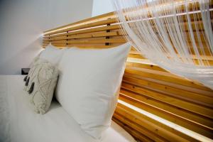 een bed met een wit kussen en een houten hoofdeinde bij YARD- Family retreat in Kórinthos