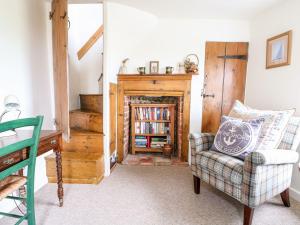 a living room with a chair and a fireplace at Beach Cottage in Holt