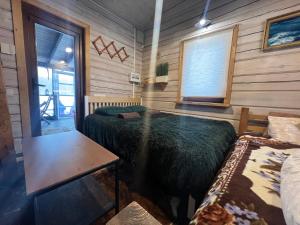 a bedroom in a log cabin with a bed and a table at Pirtelė Arjola in Kaltanėnai