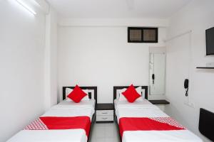 two beds in a room with red pillows at Collection O The Vinayak in Bhopal