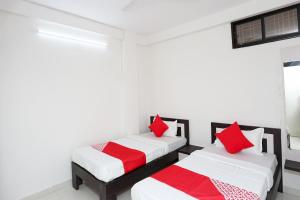 two beds in a room with red and white pillows at Collection O The Vinayak in Bhopal