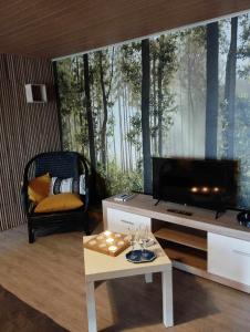 uma sala de estar com uma televisão e uma mesa em Gîte du Cheval Blanc à Houmont em Sainte-Ode