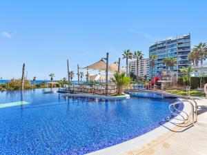 a swimming pool at a resort with palm trees and buildings at Perfect Ground Floor with Sea View in Punta Prima