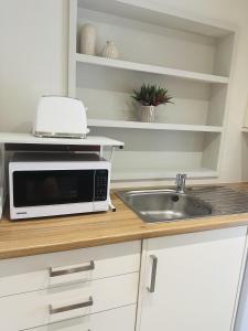 a kitchen counter with a microwave and a sink at Beautiful 1-Bed Studio in Bourne end in Bourne End