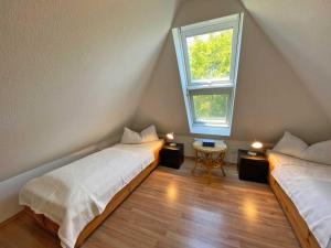 a attic room with two beds and a window at Seeschwälbchen - Ihr Ferienhaus am Ostseestrand in Zingst