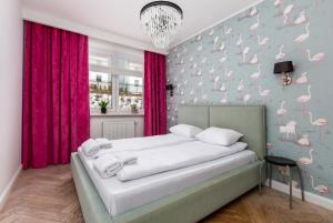1 dormitorio con 1 cama con flamencos rosas en la pared en Leśna Deluxe Apartment en Gdynia