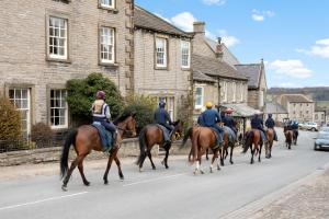 a group of people riding horses down a street at Milton House in Leyburn