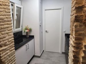 a kitchen with white cabinets and a mirror and a door at Apartamento Demasiadas Compañías in Cádiz