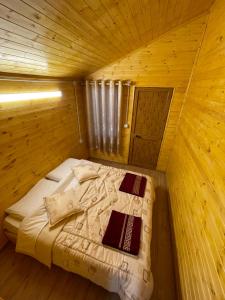 a bed in a wooden cabin with two pillows on it at Guri i Lekës Guesthouse in Shkodër