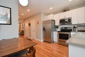 a kitchen with a table and a stainless steel refrigerator at Beautiful Home w/ Rooftop Deck Within A 5 Mintue Walk To Johns Hopkins Hospital in Baltimore