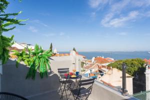 einen Balkon mit einem Tisch und Stühlen auf dem Dach in der Unterkunft MY LX FLAT Castle Alfama Apartments in Lissabon