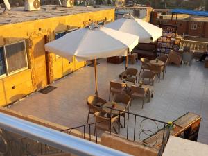 un patio esterno con tavoli, sedie e ombrelloni di Tamara Pyramids Inn a Il Cairo