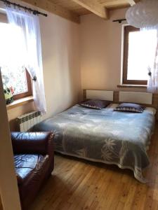 クリニツァ・ズドルイにあるDom pod Złotą Łyżwąのベッドとソファと2つの窓がある寝室 +2枚の写真