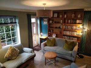 een woonkamer met 2 banken en een boekenplank bij The Whimsy 2 bedroom cottage in National Forest, private parking & garden in Blackfordby