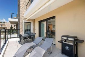 eine Terrasse mit Stühlen und einem Tisch auf dem Balkon in der Unterkunft Appartement contemporain dans résidence de standing, tout confort in Saint-Elme