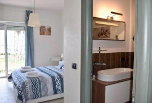 a bathroom with a bed and a sink and a mirror at Harbor Houses II in Marzamemi