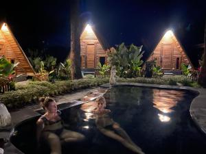 Dos mujeres tumbadas en una piscina por la noche en Triangle House and hot spring, en Kintamani