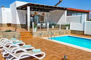 a swimming pool with lounge chairs next to a house at Caleta Blanca in La Guirra