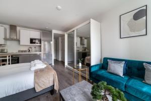 uma sala de estar com um sofá azul e uma cozinha em The Wandsworth Luxury Studio em Londres