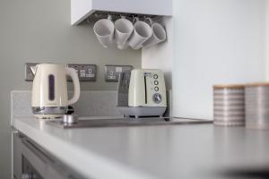 um balcão de cozinha com comodidades para preparar café e chávenas de café em The Wandsworth Luxury Studio em Londres