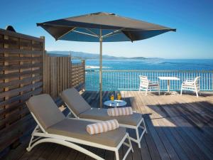a patio with two chairs and an umbrella at Sofitel Golfe d'Ajaccio Thalassa Sea & Spa in Ajaccio