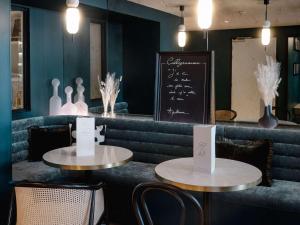 - deux tables dans un restaurant avec des chaises et un tableau noir dans l'établissement Mercure Paris Tour Eiffel Pont Mirabeau, à Paris