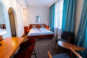um quarto de hotel com uma cama, uma mesa e cadeiras em Hotel Carlton Munich em Munique