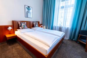 Schlafzimmer mit einem großen Bett und blauen Vorhängen in der Unterkunft Hotel Carlton Munich in München