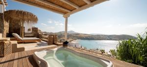 a bath tub on a deck with a view of the water at The Summit of Mykonos in Kalo Livadi