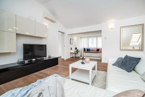 Large and stylish apartment in Prague في براغ: غرفة معيشة مع أريكة بيضاء وتلفزيون