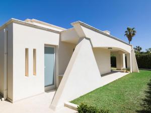 une maison blanche avec une pelouse dans l'établissement Villa SanLorenzo Beach, à Marzamemi