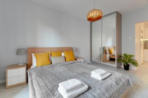a bedroom with a large bed with yellow pillows and a mirror at Staywin Aura Gdańsk I in Gdańsk
