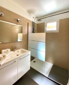 CALVI APPART HÔTEL في كالفي: حمام مع حوض ومرآة