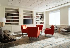 a living room with red chairs and a flat screen tv at Hilton Garden Inn Boston-Burlington in Burlington