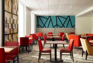 a dining room with tables and red chairs at Hilton Garden Inn Boston-Burlington in Burlington