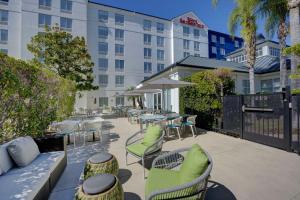 un patio avec des chaises et des tables ainsi qu'un bâtiment dans l'établissement Hilton Garden Inn Anaheim/Garden Grove, à Anaheim