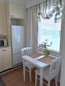 una cocina con una mesa y sillas blancas y una ventana en Tilava kt yksiö, lasitettu parveke, en Jalasjärvi