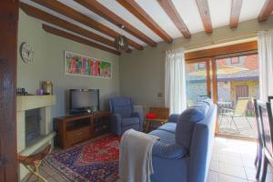 ein Wohnzimmer mit einem blauen Sofa und einem TV in der Unterkunft Las Tres Quillas in Suances
