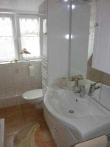 a white bathroom with a toilet and a sink at Ferienwohnung "Kleine Sandburg" in Heiligendamm