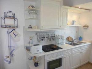 a white kitchen with a sink and a stove at Ferienwohnung "Kleine Sandburg" in Heiligendamm