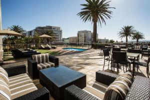 um pátio com sofás, mesas e palmeiras em Garden Court Kings Beach em Port Elizabeth