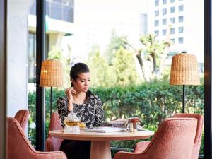 a woman sitting at a table talking on a cell phone at Mövenpick Hotel Istanbul Bosphorus in Istanbul