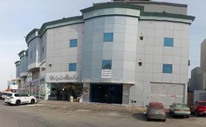 um grande edifício com carros estacionados num parque de estacionamento em شقق مفروشة شهري وسنوي em Obhor