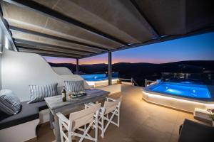 a patio with a table and chairs and a swimming pool at Myrsini's Luxury Suites Merchia in Mýkonos City