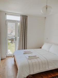 1 cama blanca en un dormitorio con ventana en East Street Beach House - luxury living by the sea en Ryde