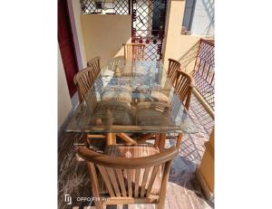 uma mesa de jantar de vidro com quatro cadeiras à volta em Gujrat Bhawan, Phata em Phata