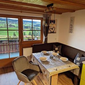 een eetkamer met een tafel, stoelen en ramen bij Ferienwohnung Alpenblick Dorner in Oberreute